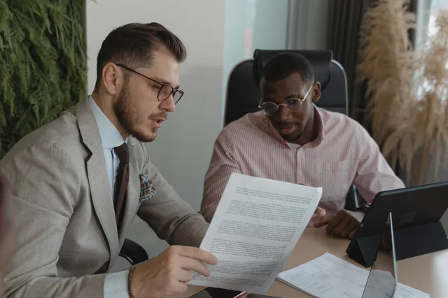 Two businessmen in an office discussing documents and working together. MarTech-Beschaffung